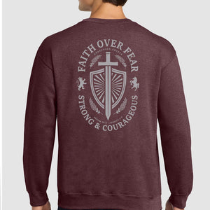 A man wearing a heathered maroon crewneck sweatshirt, viewed from the back. The sweatshirt features a large light gray graphic print on the back with a shield, sword, lions, and the text 'FAITH OVER FEAR' and 'STRONG & COURAGEOUS'.